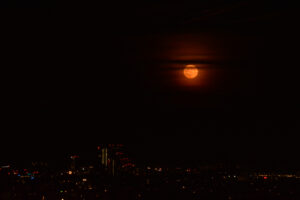 Strawberry moon rising over the Vienna skyline in a deep orange hue.
