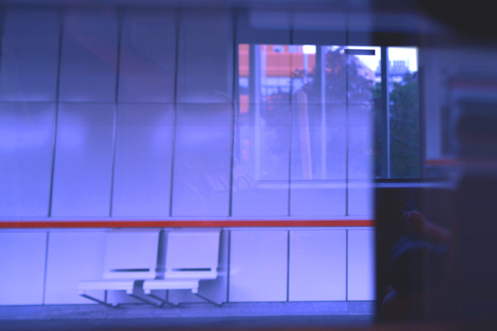 Urban photograph of a subway station on Vienna’s U3 line, featuring an arriving train, strong linear architecture, and contrasting warm and cool lighting.