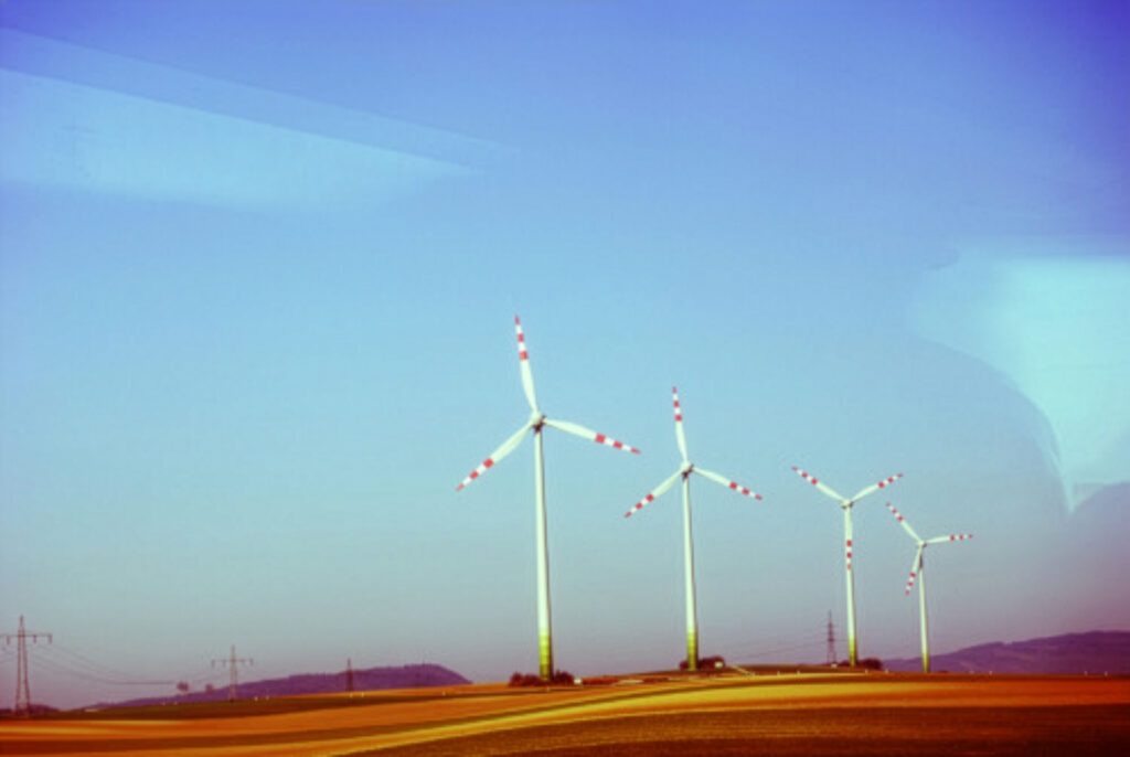 Modern wind turbines standing on rolling fields in Lower Austria under a soft pastel sky